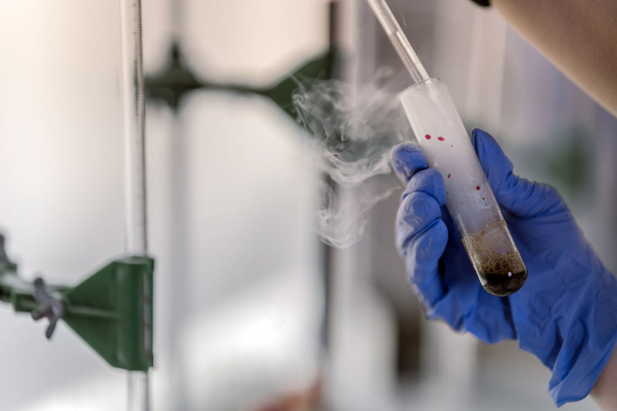 Laboratoriummedewerker houdt een reageerbuis vast tijdens chemische analyse.